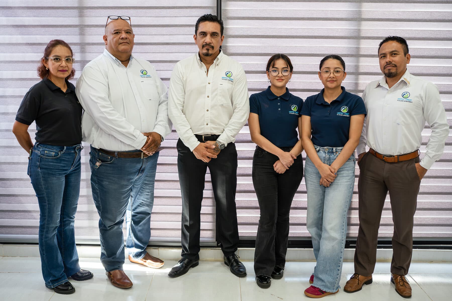 El equipo de Vertex Credit, seis personas de pie en la oficina, con el uniforme de la empresa.